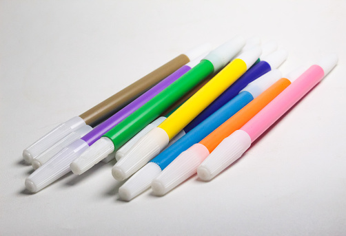 a stack of several colorful markers on a white background