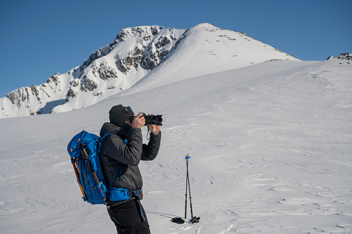 Adventure photographer prepares to shoot ski mountaineers on mountain slope