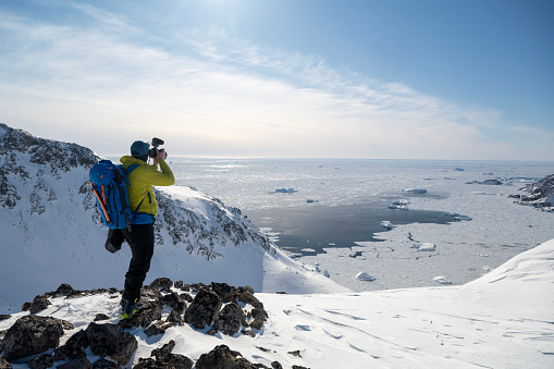 Adventure photographer prepares to shoot ski mountaineers on mountain slope