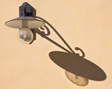 Classic streetlight against a plaster wall with shadow