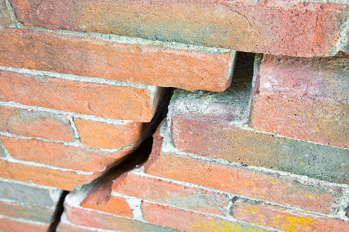 Dangerous old exposed cracked brick wall due to structural foundation failure, soil subsidence, corrosion and deterioration of building materials, earthquake