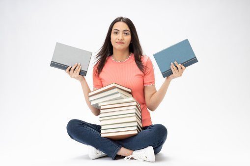 Full length body size photo of young girl book stack relaxation sitting on floor wearing jeans denim pink t-shirt footwear isolated over white background