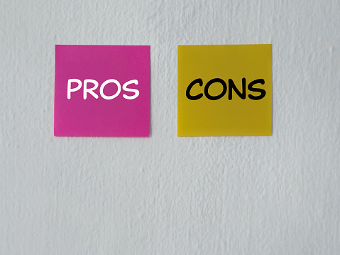 PROS and CONS written on adhesive papers. With white blurred vintage styled background.