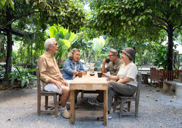 Asian senior talking and drinking coffee at garden