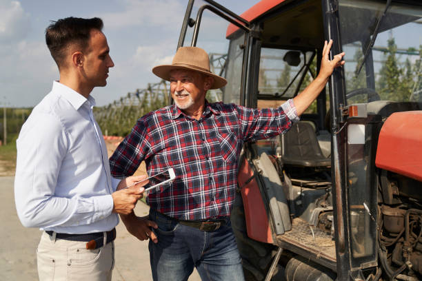 istock Senior farmer and sales representative next to tractor talking over digital tablet 2116610666