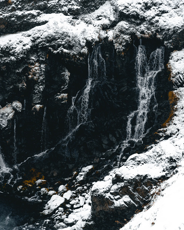 The water cascades down the side of a snowy cliff