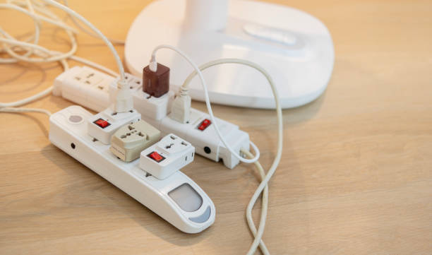 istock Messy outlet power extension cord on an apartment floor with various charging devices 2116635901