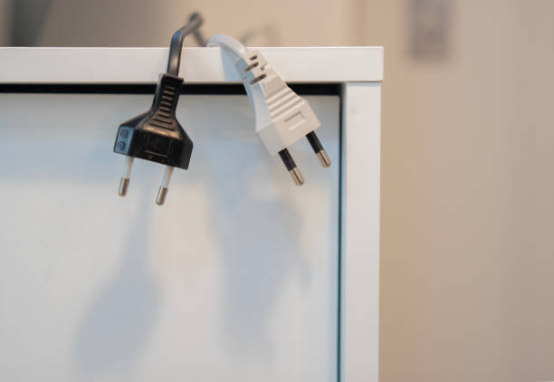 istock Black and white electric plugs hanging from the sideboard cabinet at office. 2116636030