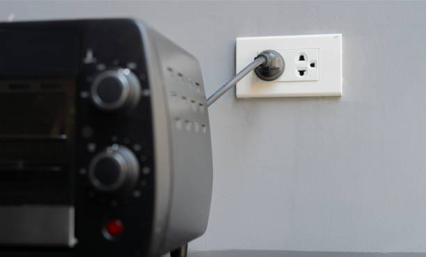 istock Shot image of black mini electric oven with plugin outlet power at wall background. 2116647029