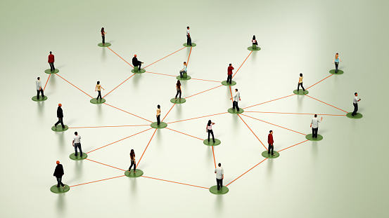 An arrangement of miniature human figures stands on a bright white backdrop, interconnected by thin black lines that simulate a network or a web of social or professional relationships. The figures vary in posture and orientation, suggesting dynamic interaction or communication paths within a simplified model of a community or organization structure.