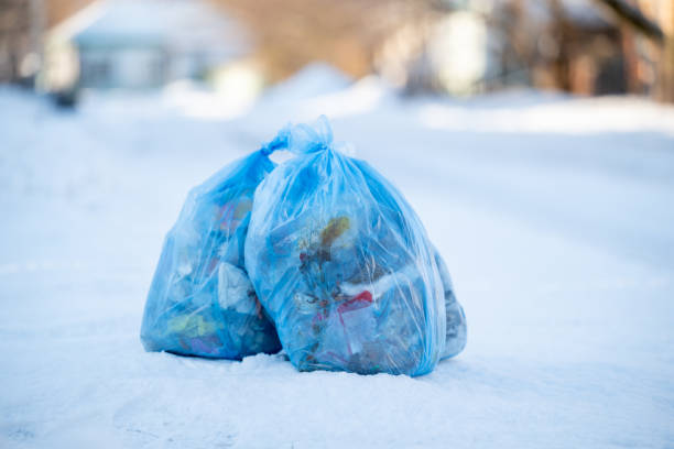 istock Blue plastic garbage bags on the roadside on sunny day in winter 2116682040