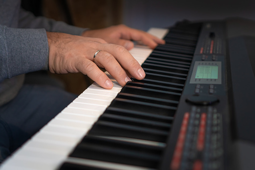 Close-up of male hands playing an electronic piano. Musical education at a music school. Private music lessons with a teacher.
