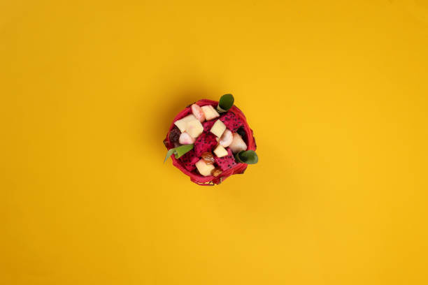 istock Beautiful Mangosteen mango dragon fruit cube fruit salad in dragon fruit skin bowl on yellow background green banana leaf 2116697370