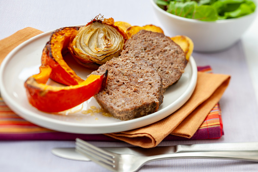 Food and drink: plate of homemade ground beef Meatloaf with onion and pumpkin roasted from the oven, studio shot.