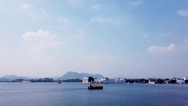 A Dramatic view of the Udaipur palace against the clouds and pristine waters in the city of Lakes in Rajasthan, India.