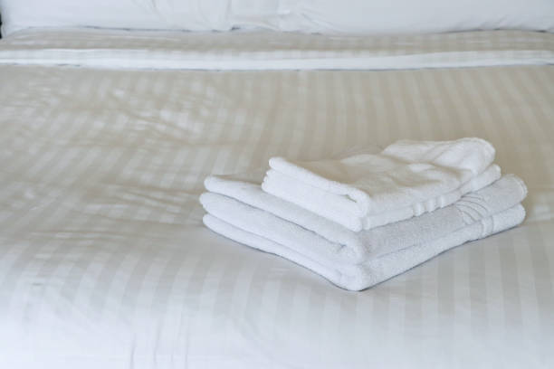 istock Image of cosy hotel bedroom, folded white towels, bed sheets, quilt, and pillow with ample copyspace 2116730255