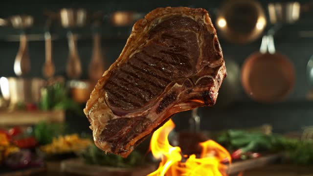Super Slow Motion of Flying Beef Steak above Grill.