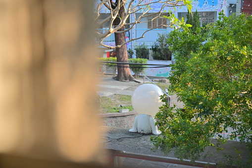 The silhouette of a lightbulb figure on the wall silently watches over the once bustling village.