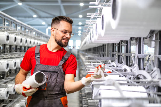 istock Working in textile factory controlling knitting machine. 2116771161