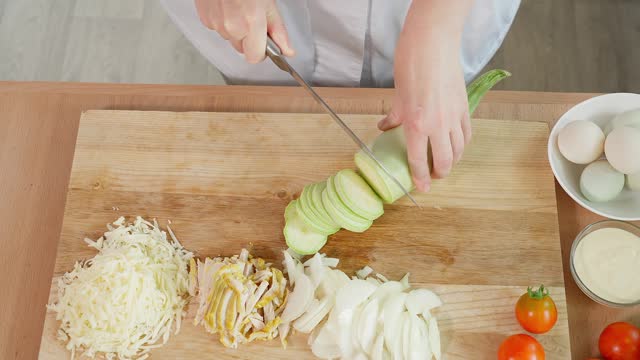 The chef cuts white zucchini into slices with a sharp knife. Healthy eating concept, vegetarian food, vegetables rich in vitamins, diet. Close-up, top view