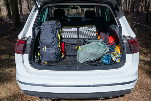 Hiking and camping equipment in the open trunk of an SUV in the forest