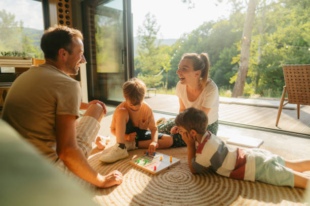 Playing board games together Photo of a young family playing board games together on the floor of their home good family stock pictures, royalty-free photos & images