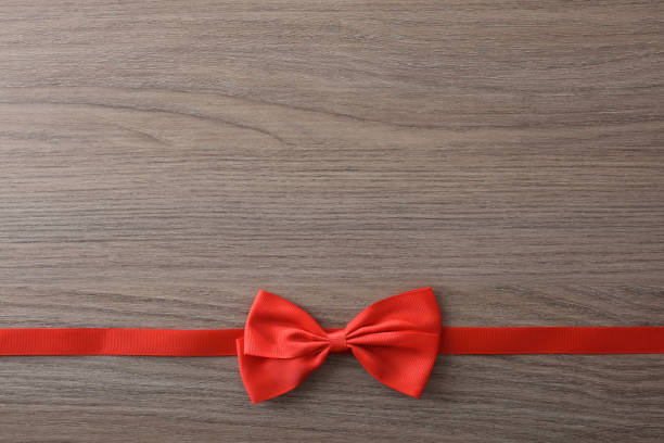 Bright yellow wrapped gift with a red bow sitting on a tabletop, symbolizing celebration and holiday cheer.