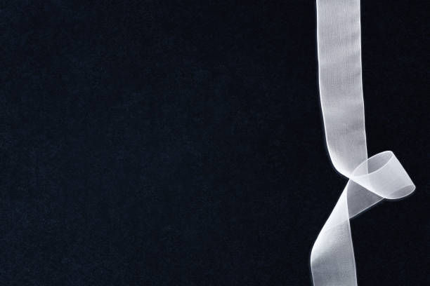 White tulle ribbon with waves on right side on textured isolated dark background. Top view.