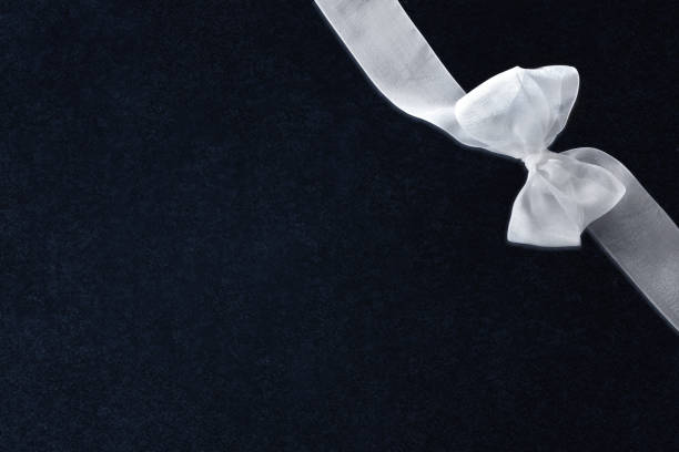 White tulle bow with ribbon in the upper right corner on textured isolated dark background. Top view.
