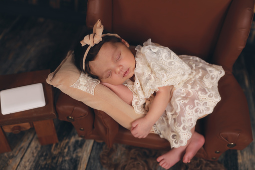 a newborn sleeping on a brown leather chair