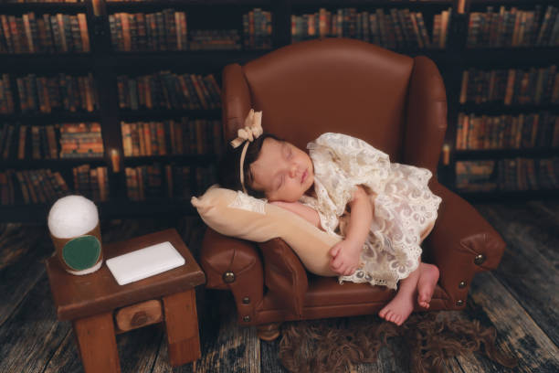 a newborn sleeping on a brown leather chair