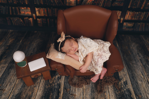 a newborn sleeping on a brown leather chair