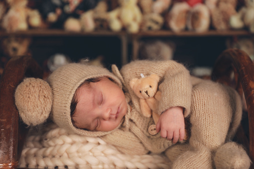 a newborn baby sleeping in a basket with teddy bears