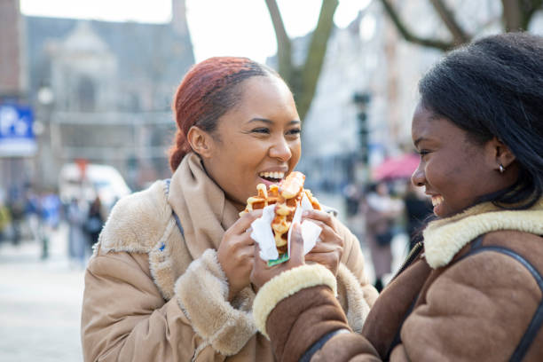 two young women eating waffles in brussels - brussels waffle belgian waffle people imagens e fotografias de stock