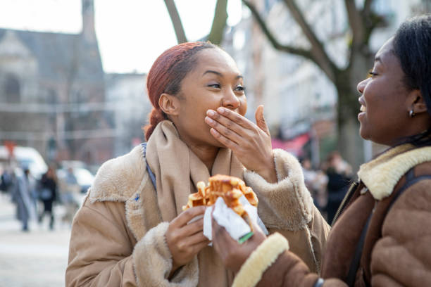 two young women eating waffles in brussels - brussels waffle belgian waffle people imagens e fotografias de stock