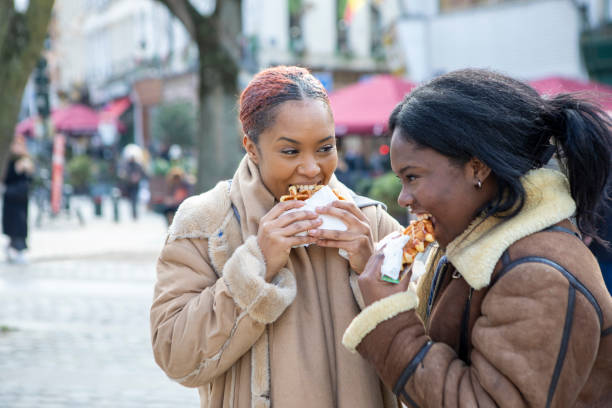 two young women eating waffles in brussels - brussels waffle belgian waffle people fotografías e imágenes de stock