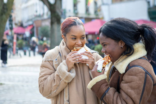 two young women eating waffles in brussels - brussels waffle belgian waffle people imagens e fotografias de stock