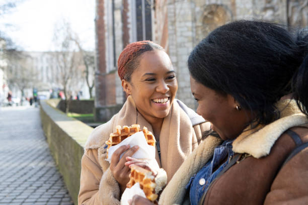 two young women eating waffles in brussels - brussels waffle belgian waffle people fotografías e imágenes de stock