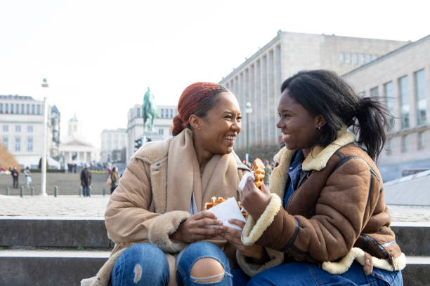 two young women eating waffles in brussels - brussels waffle belgian waffle people fotografías e imágenes de stock