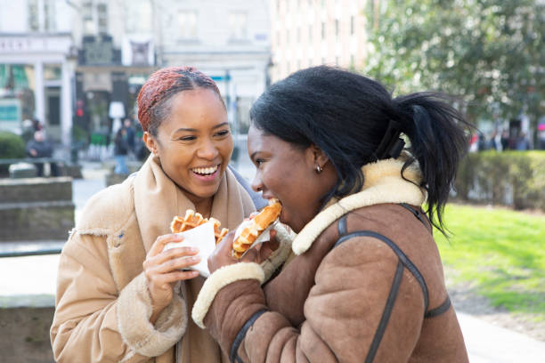 dos mujeres jóvenes comiendo gofres en bruselas - brussels waffle belgian waffle people fotografías e imágenes de stock