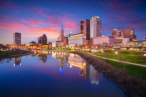 Cityscape image of Columbus, Ohio, USA downtown skyline with the reflection of the city in the Scioto River at spring sunset.