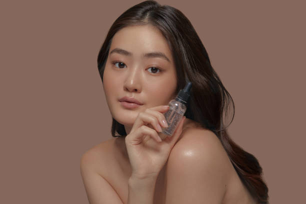 istock Charming asian ethnicity young model with a fresh smooth skin holding face moisturizer serum on a beige background 2116857800
