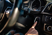 Woman pressing the engine start stop button of a car.