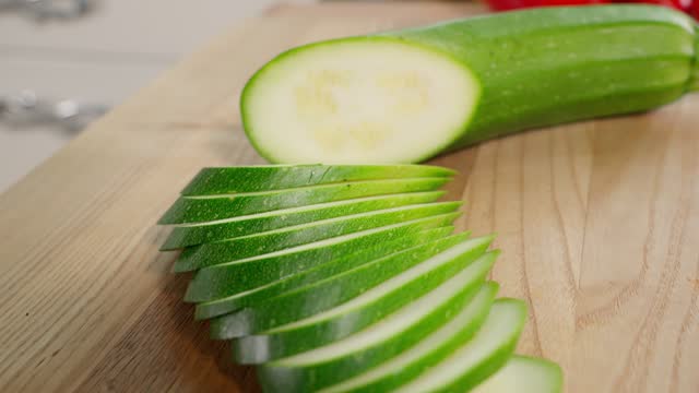 Sliced green zucchini into slices on a wooden board. Healthy eating concept, vegetarian food, rich in vitamins, diet, vegetables. Close-up, front view, macro
