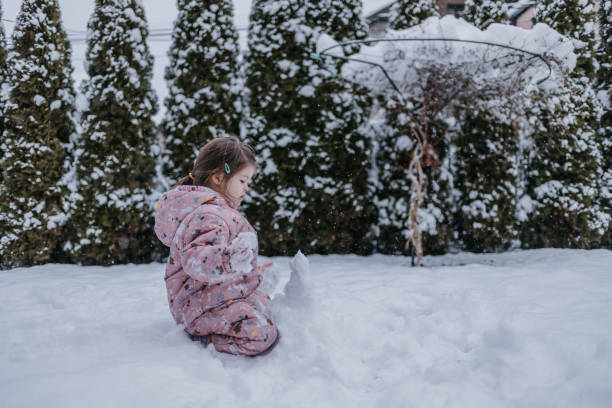 istock The toddler is making a snowman in the yard. 2116881172