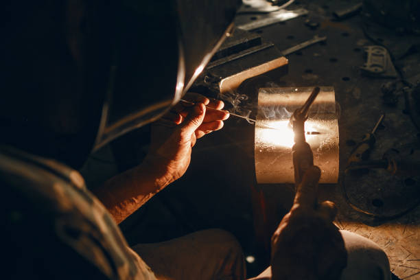 istock Man working with arc welding machine in garage. Metalwork manufacturing and construction maintenance service. Industrial welder worker welding using argon machine, close up. 2116887434