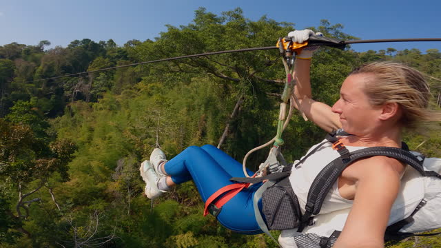 Young woman zip lining in the jungle of Laos