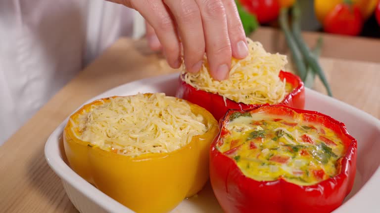 The chef sprinkles stuffed yellow and red peppers, paprika, and stuffed yellow peppers with grated cheese. Vegetables, vegetarian food, rich in vitamins, healthy eating concept. Macro