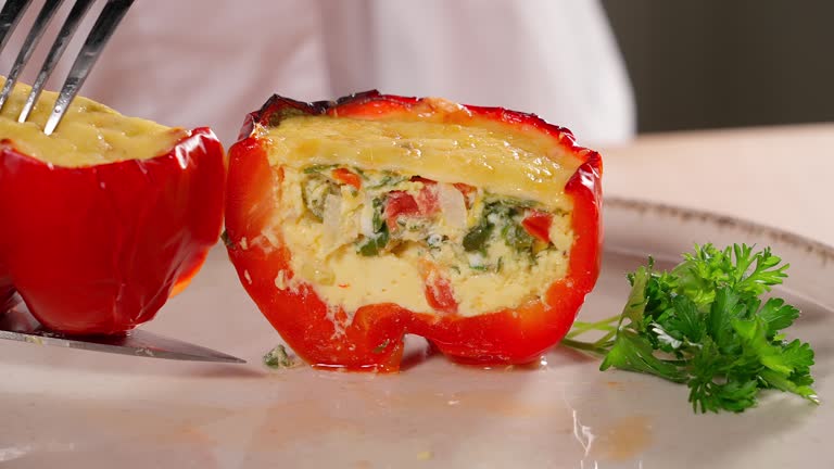 Cut ready stuffed red pepper with a mixture of eggs and vegetables, paprika. Vegetables, vegetarian food, rich in vitamins, healthy eating concept. Macro