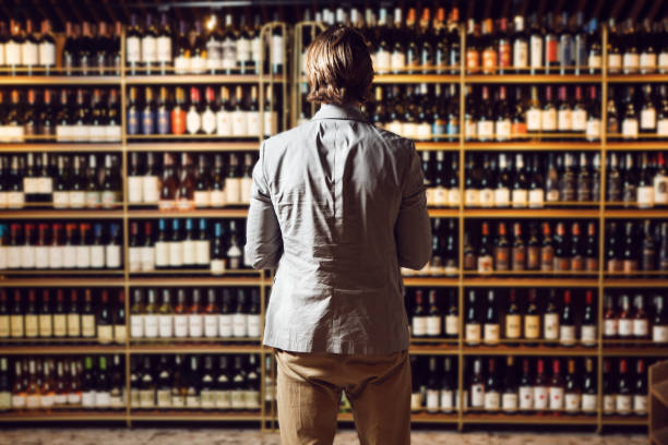 istock Male bartender at wine cellar full of bottles with exquisite drinks 2116919618